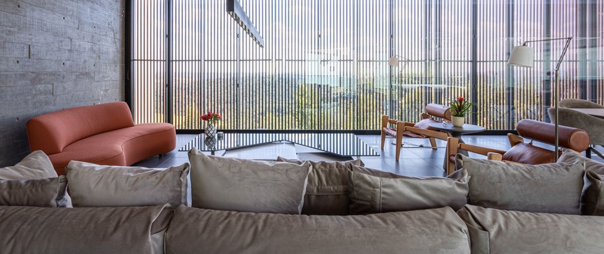 a living room filled with lots of furniture and a large windows in the center of it next to a window covered in front of a window covered in a room filled with lots of plants and bookshelves covered